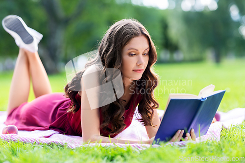 Image of happy young woman reading book at summer park