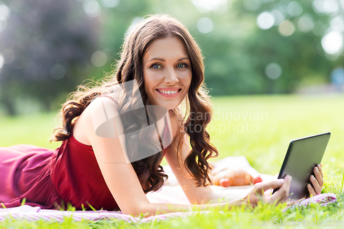 Image of happy woman with tablet computer on picnic at park