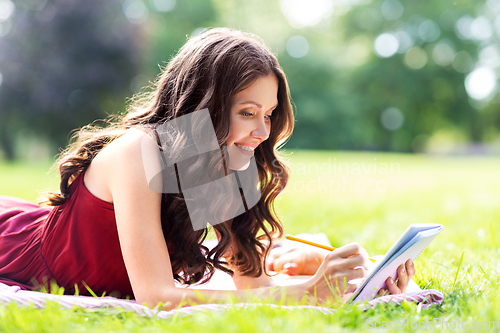 Image of happy woman with diary or notebook at park