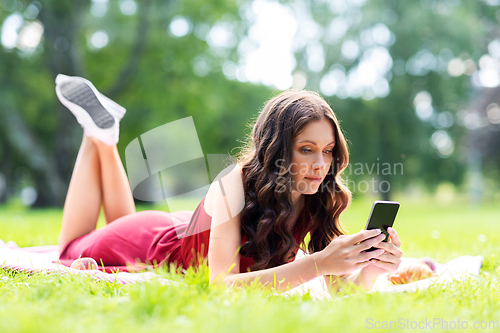 Image of beautiful young woman with smartphone at park