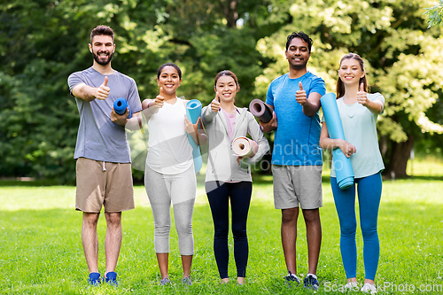 Image of people with yoga mats showing thumbs up at park