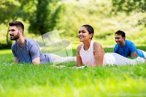 Image of group of people doing yoga at summer park