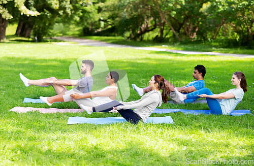 Image of group of people doing yoga at summer park