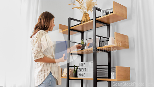 Image of woman arranging flower and books at home