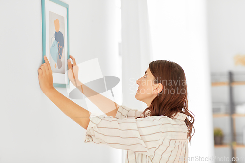 Image of woman decorating home with picture in frame