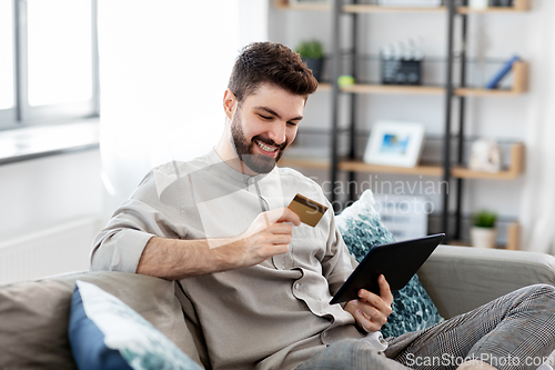 Image of man with tablet computer and credit card at home