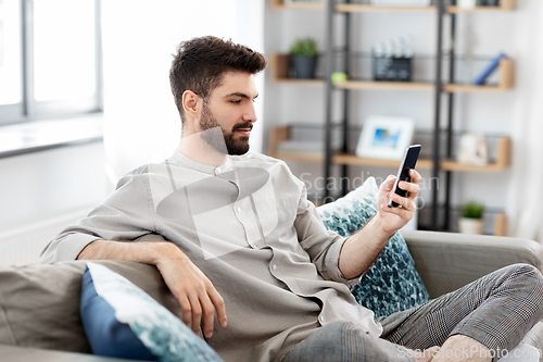 Image of young man with smartphone at home