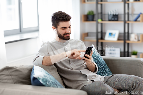 Image of man in earphones listening to music on smartphone