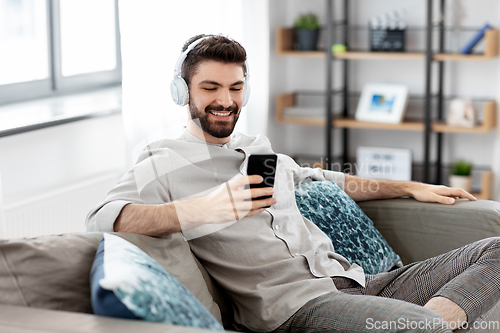 Image of man in headphones listening to music on smartphone