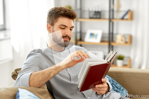 Image of man reading book at home