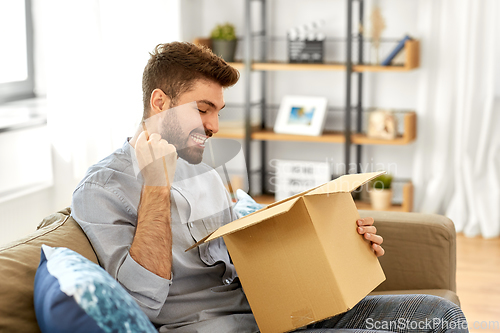 Image of happy man opening parcel box at home