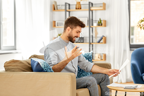 Image of man with bills counting on calculator at home