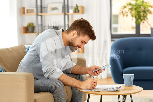 Image of man with money and calculator filling papers