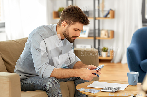 Image of man with money and calculator filling papers