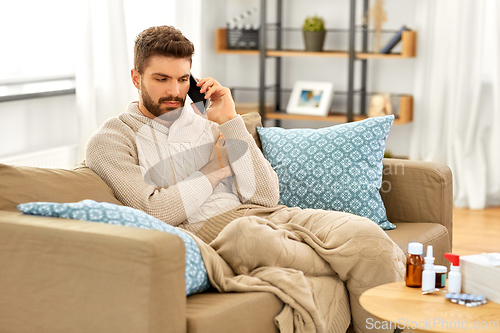 Image of sick young man calling on smartphone at home