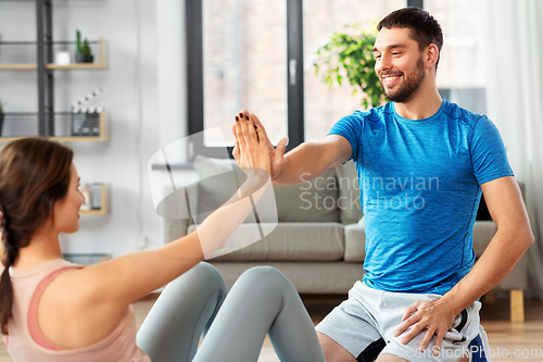 Image of woman with personal trainer doing sit ups at home