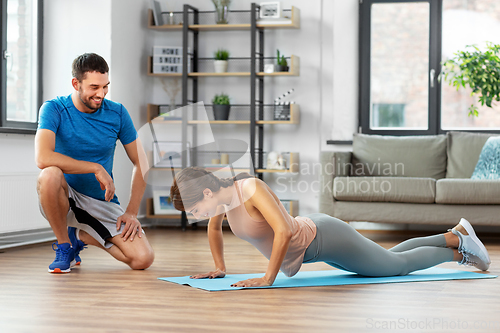 Image of woman with personal trainer doing push-ups at home