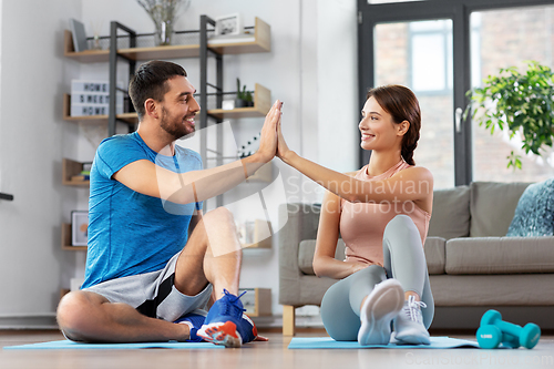 Image of couple doing sports and making high five at home