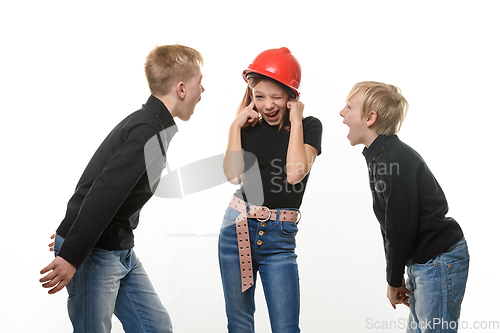 Image of Two boys are shouting at a girl, the girl is standing in a helmet in a helmet and plugged her ears