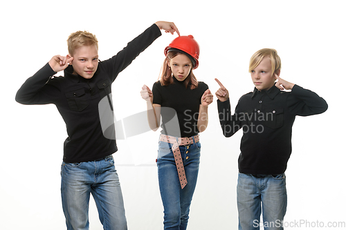 Image of Two boys are disgusted by the presence of a girl, a girl in a hard hat and shows them a figure