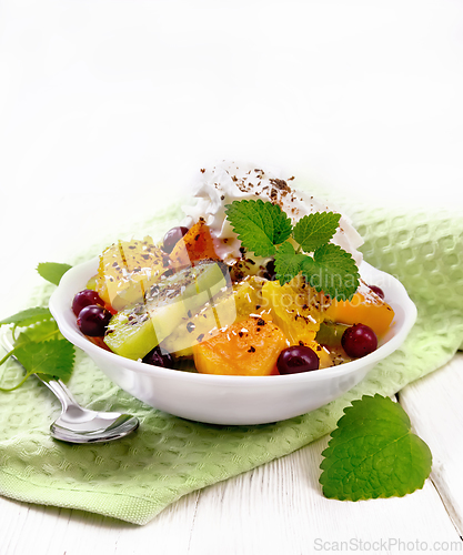 Image of Salad fruit with cranberries in bowl on light wooden board