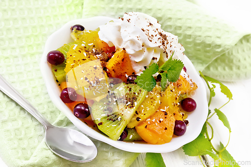 Image of Salad fruit with cranberries in bowl on white wooden board