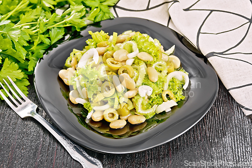 Image of Salad of beans and olives in plate on dark board