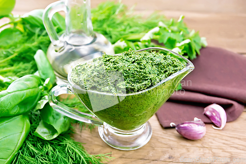 Image of Sauce of spicy greens in gravy boat on old board