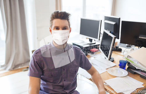 Image of male office worker in mask with computers