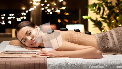 Image of smiling woman having hot stone massage at spa