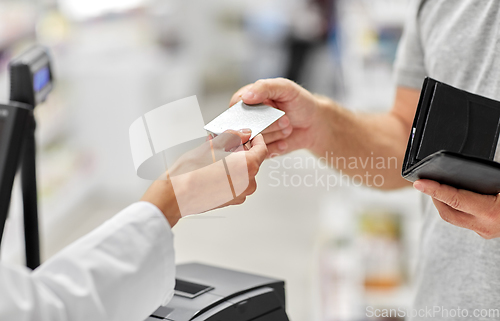 Image of close up of hand giving bank card to pharmacist