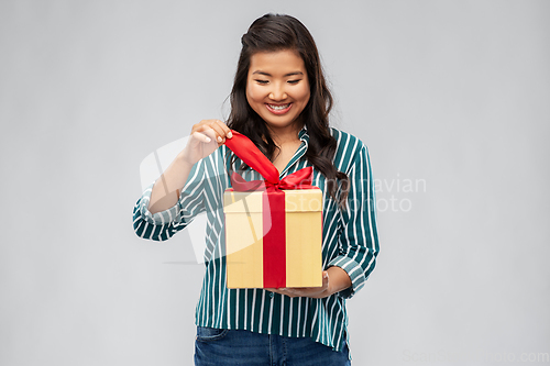 Image of happy asian woman opening gift box