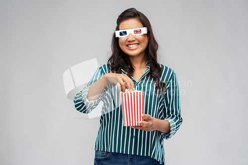 Image of asian woman in 3d movie glasses eating popcorn