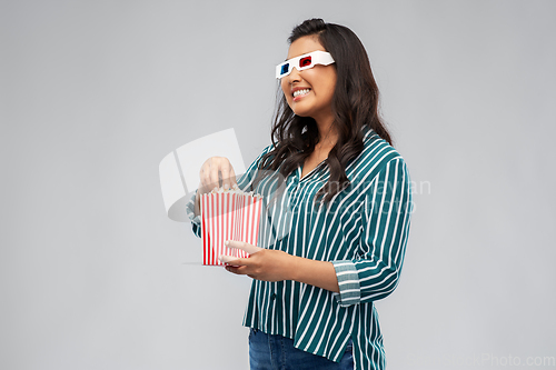 Image of asian woman in 3d movie glasses eating popcorn