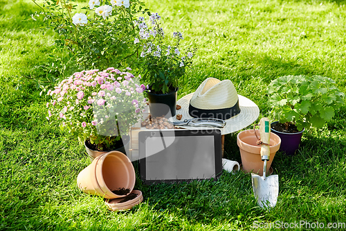 Image of tablet pc, garden tools and flowers at summer