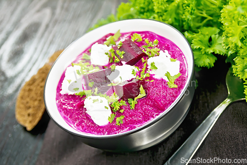Image of Soup puree of beetroot with salted cheese in bowl on black board