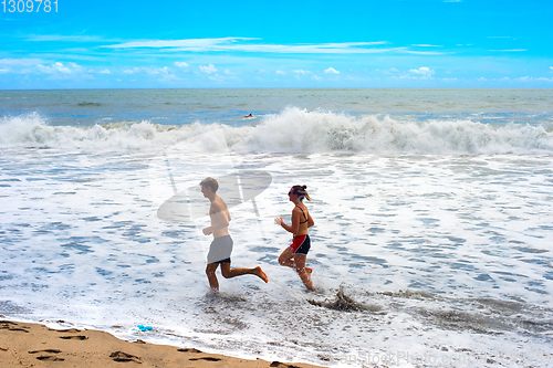 Image of Couple running ocean beach Bali