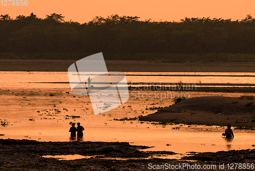 Image of Asian women fishing in the river, silhouette at sunset