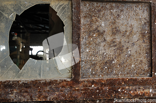 Image of rusty factory door and smashed glass