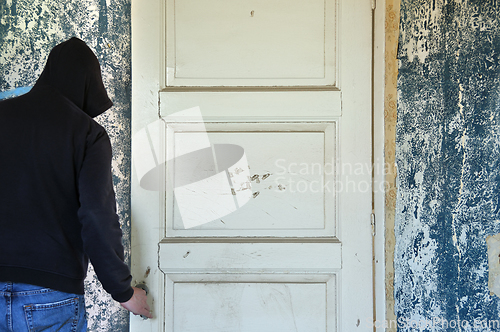 Image of man opening door of decayed room