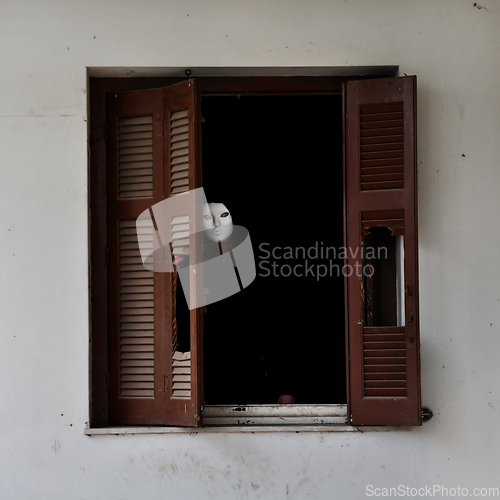 Image of masked figure and broken window shutter