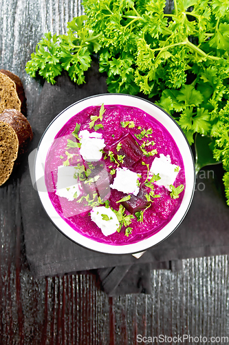 Image of Soup puree of beetroot with salted cheese in bowl on dark board 