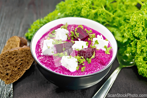 Image of Soup puree of beetroot with salted cheese in bowl on dark board