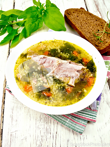 Image of Soup with couscous and spinach in plate on board