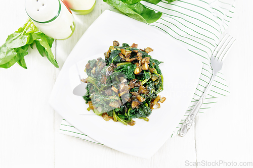 Image of Spinach fried with onions in plate on board top