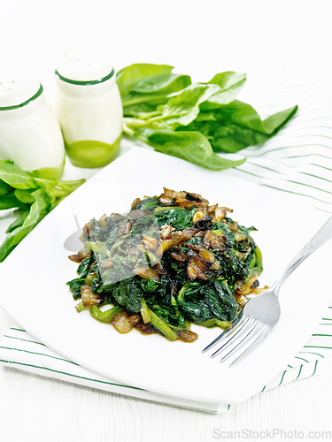 Image of Spinach fried with onions in plate on napkin