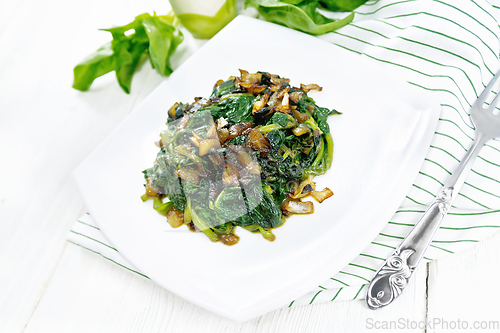 Image of Spinach fried with onions in plate on white board