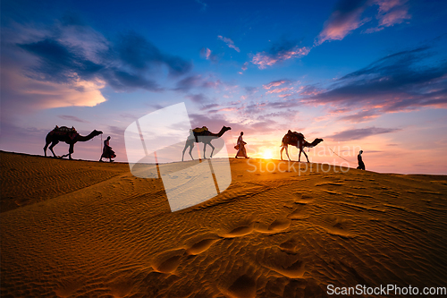 Image of Indian cameleers camel driver with camel silhouettes in dunes on sunset. Jaisalmer, Rajasthan, India