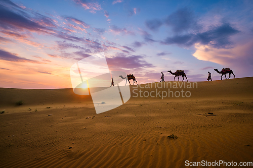 Image of Indian cameleers camel driver with camel silhouettes in dunes on sunset. Jaisalmer, Rajasthan, India