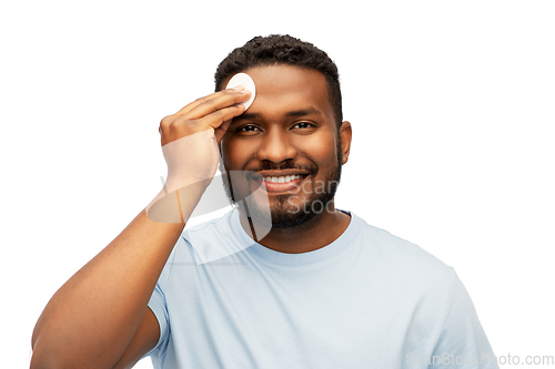 Image of african american man cleaning face with cotton pad